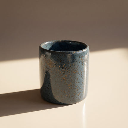 Handcrafted Glazed Clay Vessel in dark teal reactive glaze, on a warm cream background