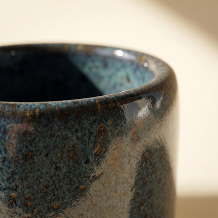 Close-up of the speckled bronze and teal glaze on the rim of the Handcrafted Glazed Clay Vessel